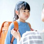 小学生の女の子を見つめる母親