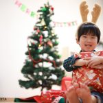 クリスマスツリーの前でプレゼントを抱えた男の子