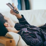 寝ながらスマホを触る男性