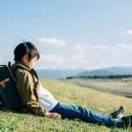 草原に座る小学生の男の子