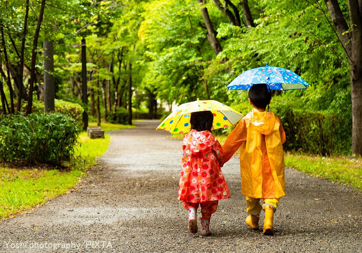 雨の中傘を指して歩く男の子と女の子