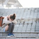 膝を抱えて落ち込む小学生