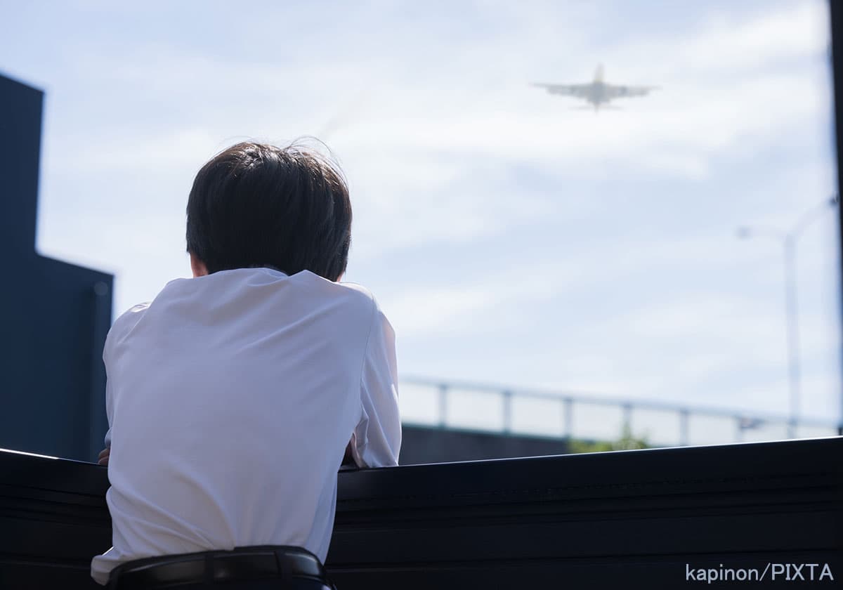 飛行機を眺める中学生の後ろ姿