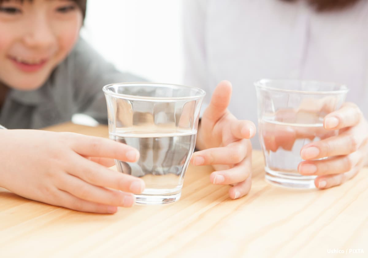 コップで水を飲む女の子とママ