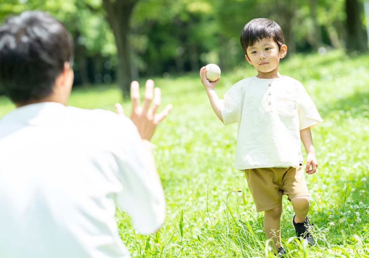 野球ボールで父親とキャッチボールする未就学児の男の子