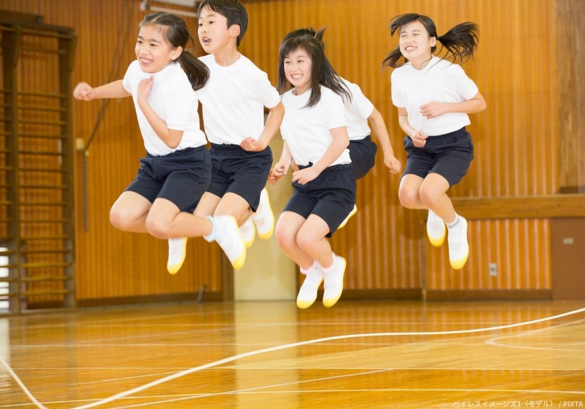 体育館で大縄跳びをする小学生