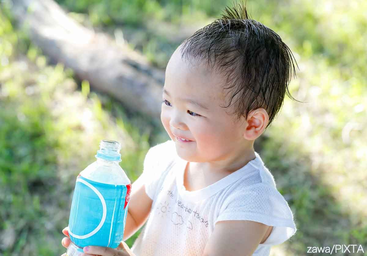 夏に汗をかきながら飲み物を飲む子ども