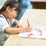 スケッチブックに絵を描く小学生の女の子