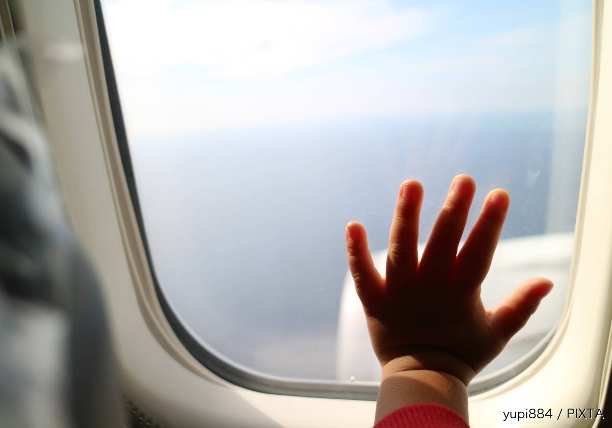 飛行機の窓と子どもの手